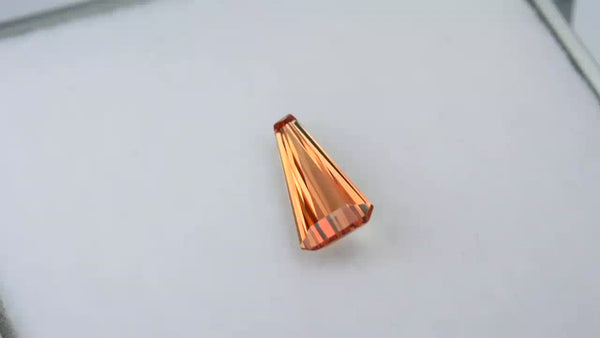 Custom tapered-cut orangey pink Padparadscha sapphire.